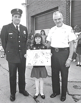 Chief John Helfert and Lieutenant Steven Guetschow with Girl Who Won Poster Contest